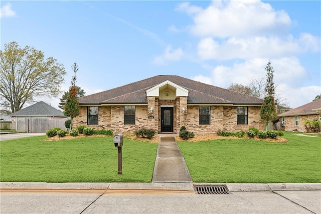 view of front of home with brick siding, a front lawn, and fence