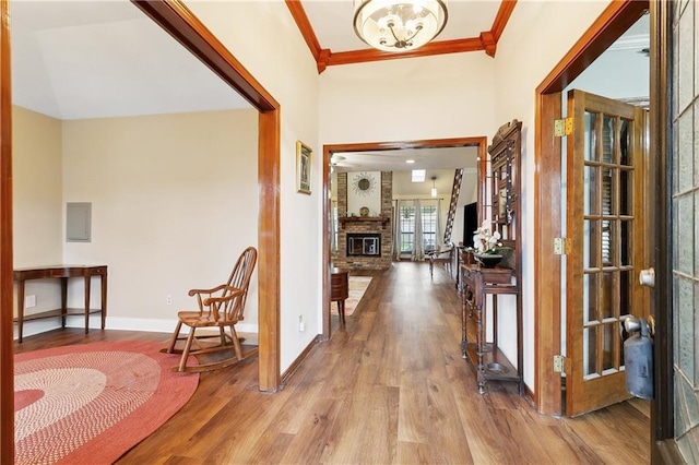 foyer featuring a fireplace, crown molding, wood finished floors, and baseboards