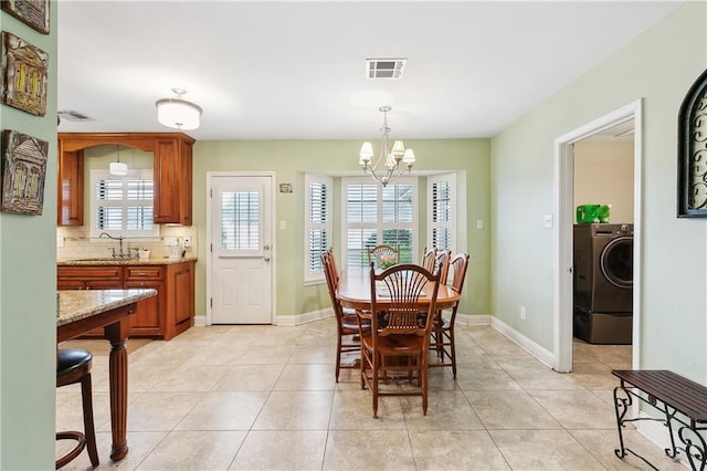 dining room featuring light tile patterned floors, baseboards, visible vents, washer / dryer, and a chandelier