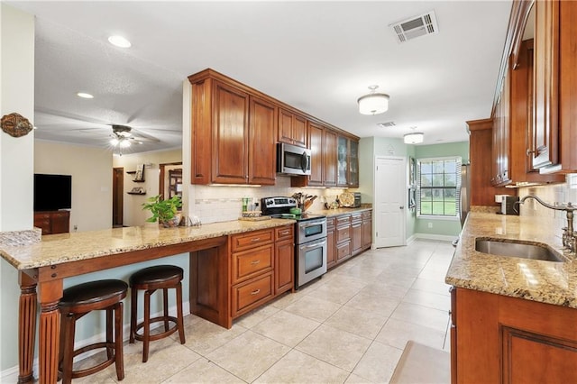 kitchen with visible vents, a sink, tasteful backsplash, appliances with stainless steel finishes, and light stone countertops