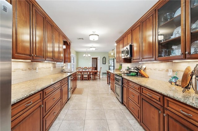 kitchen with visible vents, light stone countertops, appliances with stainless steel finishes, an inviting chandelier, and light tile patterned flooring