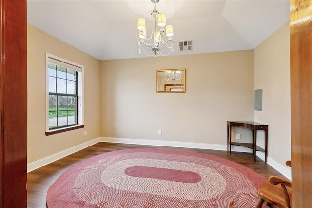 empty room with visible vents, dark wood-type flooring, an inviting chandelier, and vaulted ceiling