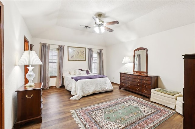 bedroom featuring a tray ceiling, lofted ceiling, wood finished floors, and a ceiling fan