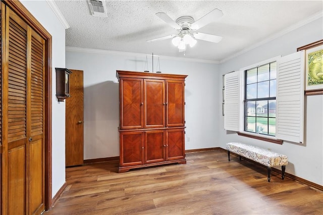 unfurnished bedroom featuring a textured ceiling, light wood-type flooring, visible vents, and ornamental molding