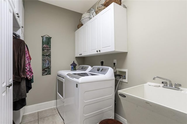 laundry area featuring a sink, washing machine and dryer, light tile patterned flooring, baseboards, and cabinet space