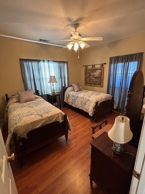 bedroom with wood finished floors, a ceiling fan, and visible vents