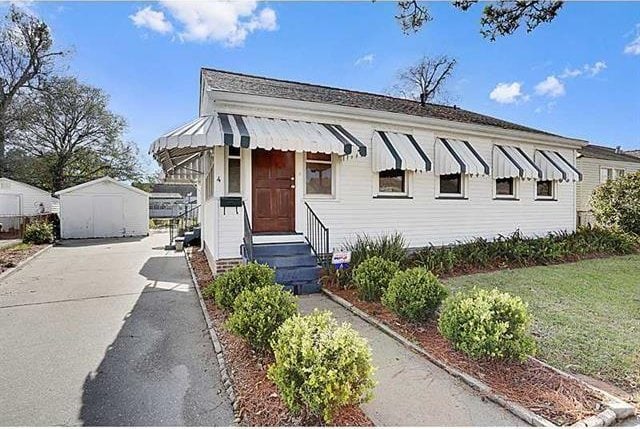 view of front of house with a storage unit, an outbuilding, a front lawn, driveway, and entry steps