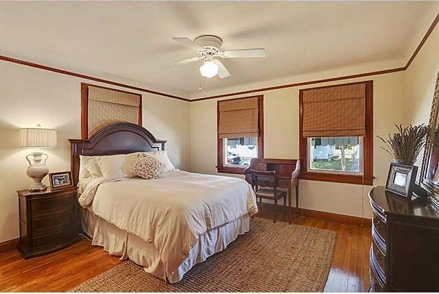 bedroom with a ceiling fan, wood finished floors, baseboards, and ornamental molding