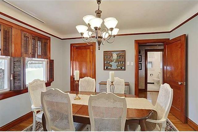 dining space with a notable chandelier, wood finished floors, baseboards, and ornamental molding