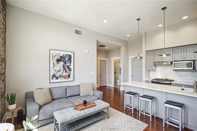 living room with recessed lighting, dark wood-style floors, and visible vents