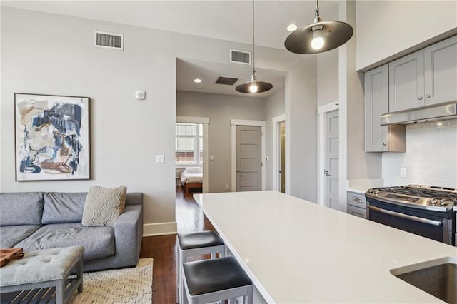 kitchen featuring decorative backsplash, gas range, light countertops, and gray cabinets