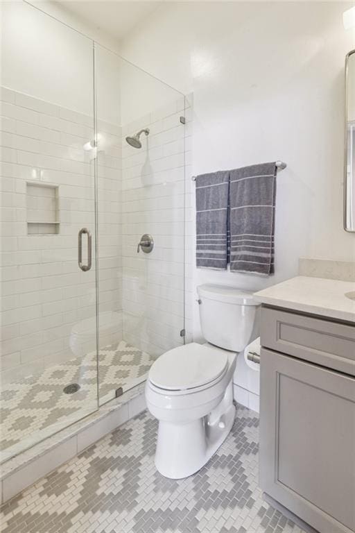 bathroom featuring vanity, tile patterned floors, toilet, and a stall shower