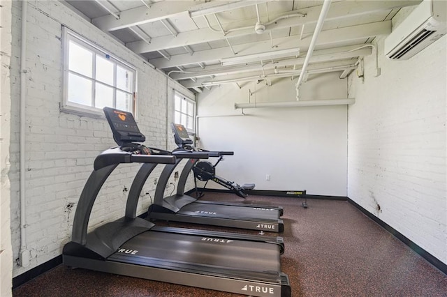 exercise area with baseboards, brick wall, and a wall unit AC