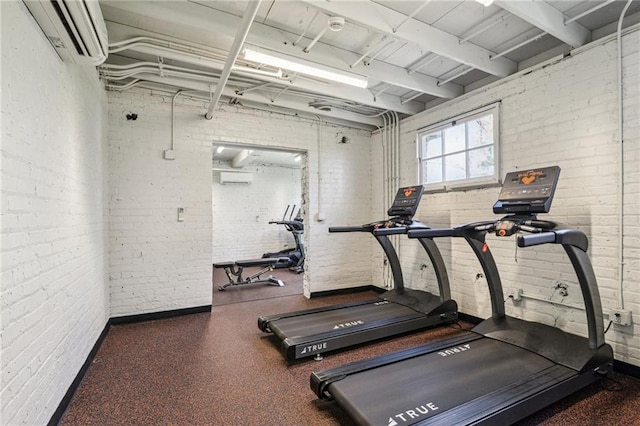 exercise room with a wall unit AC and brick wall