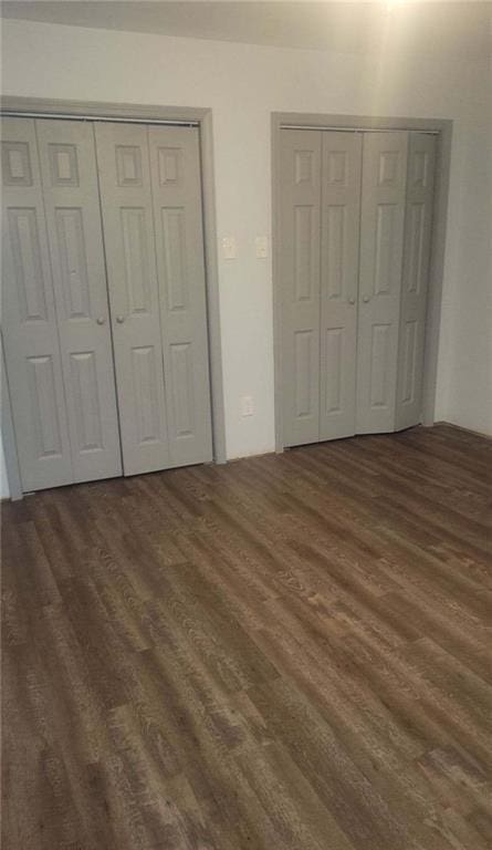 unfurnished bedroom featuring multiple closets and wood finished floors