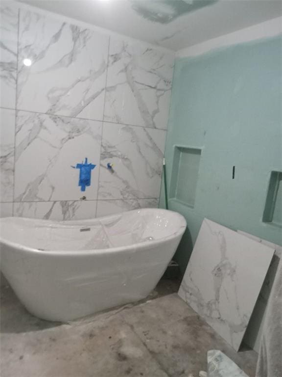 full bath with a freestanding bath and marble finish floor