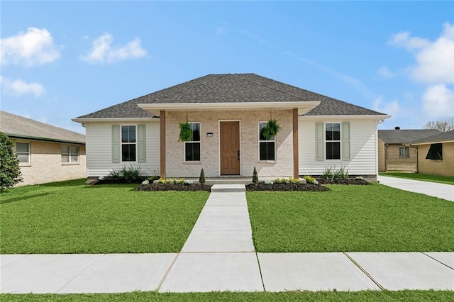 view of front facade with a front lawn, brick siding, and roof with shingles