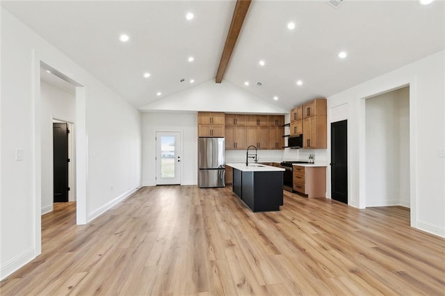 kitchen featuring open floor plan, light countertops, beam ceiling, stainless steel appliances, and a kitchen island with sink