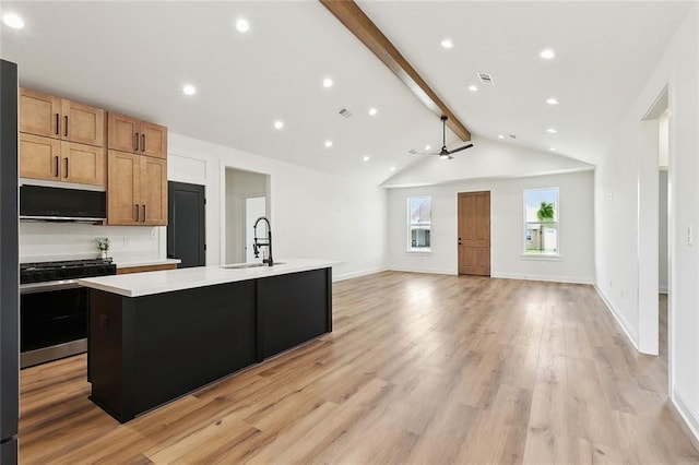 kitchen with visible vents, an island with sink, light countertops, stainless steel gas range, and a sink