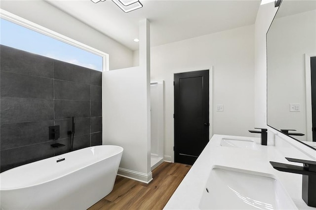 full bath with a sink, a freestanding bath, wood finished floors, and a walk in shower