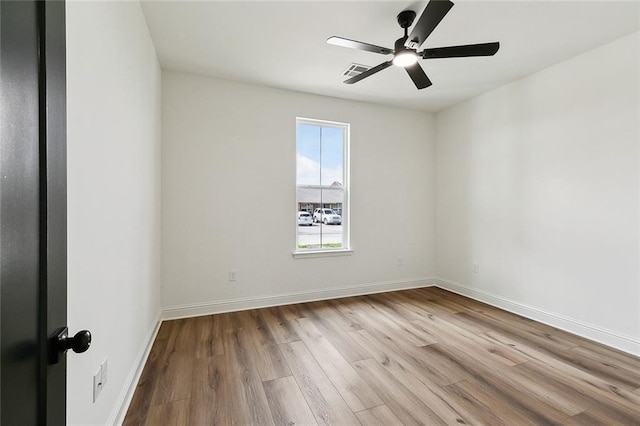 spare room with visible vents, wood finished floors, baseboards, and ceiling fan