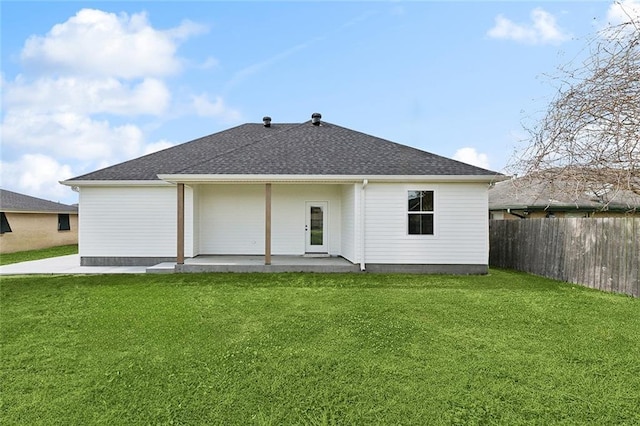 rear view of house featuring a lawn, a shingled roof, a patio, and fence