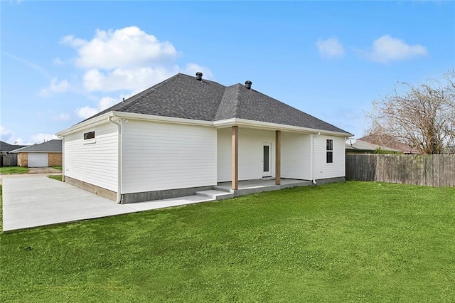 back of property featuring a yard, a patio area, fence, and roof with shingles