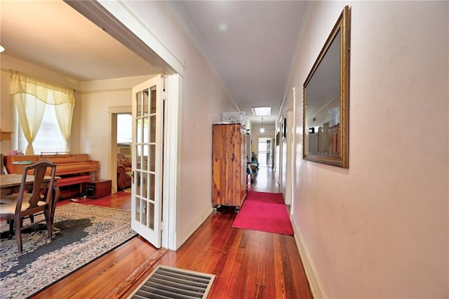 corridor with crown molding, baseboards, and hardwood / wood-style flooring