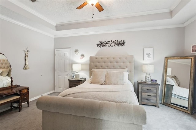 carpeted bedroom featuring a raised ceiling, ornamental molding, a ceiling fan, a textured ceiling, and baseboards