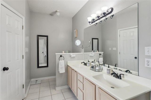 full bathroom with tile patterned flooring, double vanity, a textured ceiling, and a sink