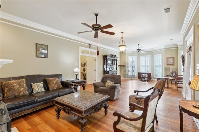 living area with visible vents, wood finished floors, ceiling fan, and ornamental molding