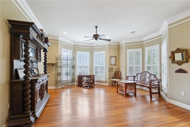 living area featuring visible vents, crown molding, light wood finished floors, baseboards, and ceiling fan