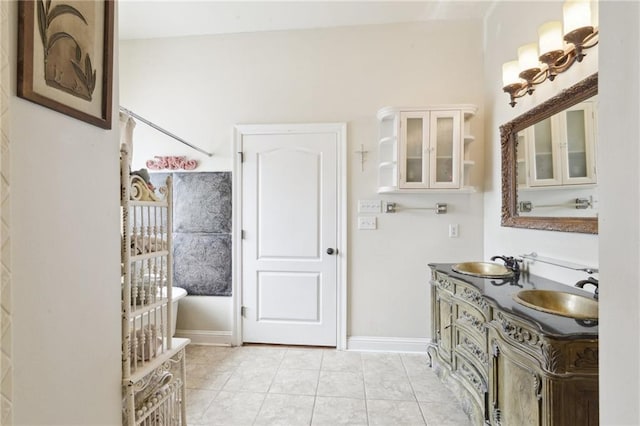 bathroom featuring tile patterned floors, double vanity, baseboards, and a sink