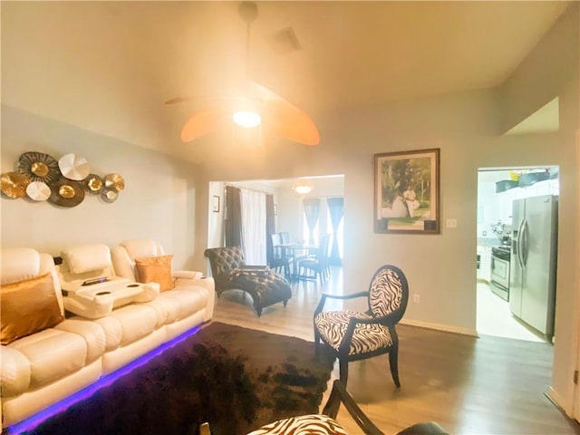 living room featuring baseboards, ceiling fan, and wood finished floors