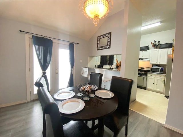 dining room featuring light wood-type flooring, baseboards, an inviting chandelier, and vaulted ceiling