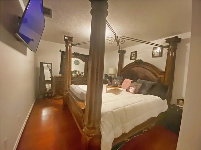 bedroom featuring wood finished floors, baseboards, and a textured ceiling