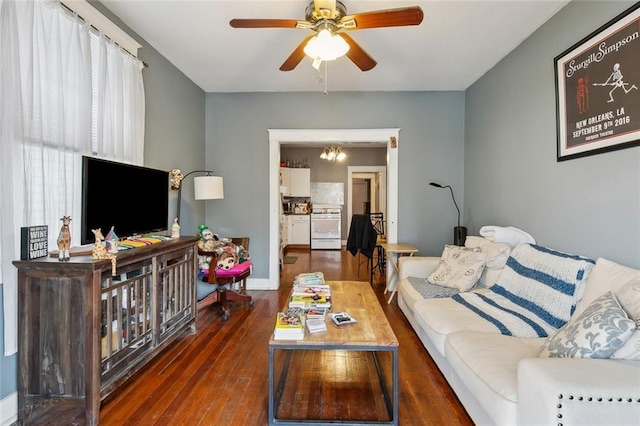 living area featuring ceiling fan with notable chandelier, baseboards, and hardwood / wood-style floors