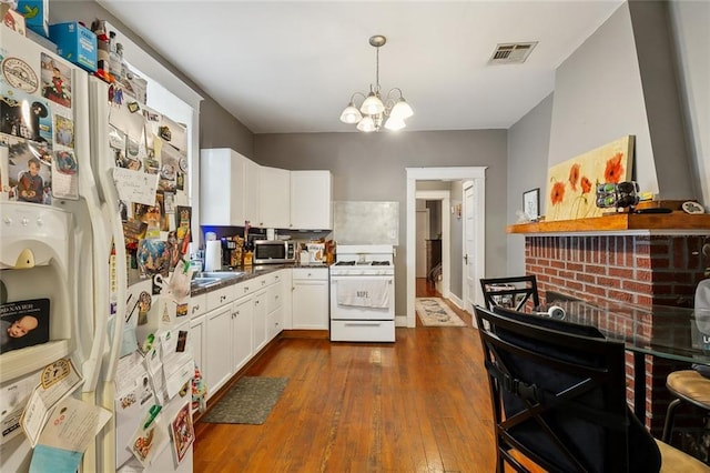 kitchen featuring visible vents, dark countertops, white cabinetry, white appliances, and a chandelier