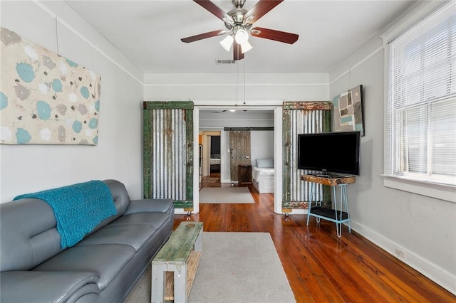 living room with wood finished floors, a ceiling fan, visible vents, and baseboards