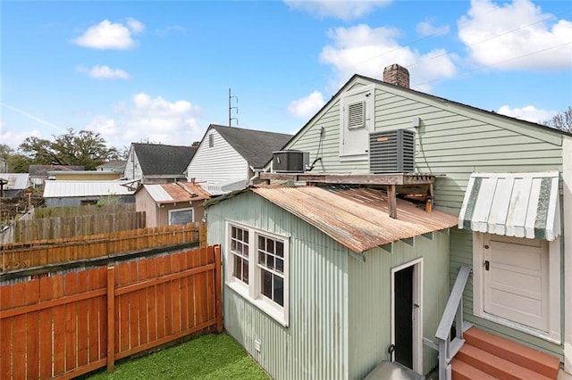 exterior space with a chimney, central AC, and fence