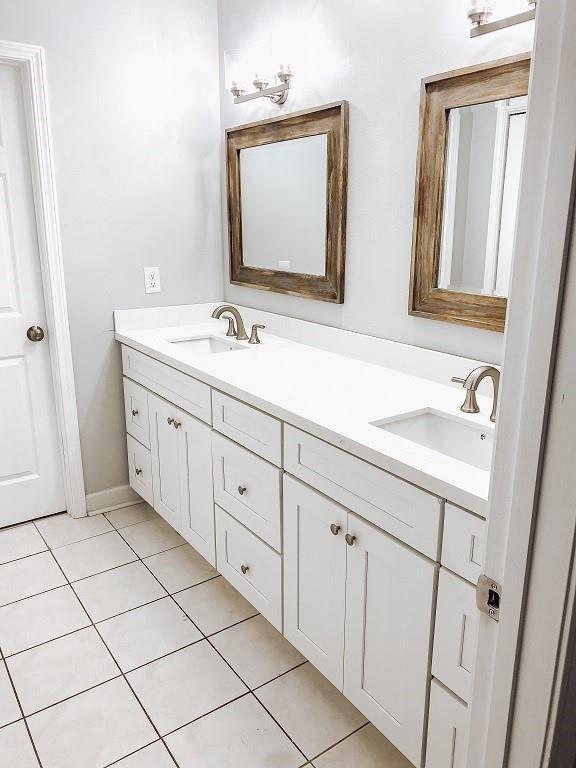 full bathroom featuring a sink, double vanity, and tile patterned flooring