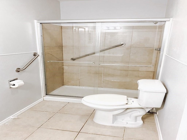 bathroom with tile patterned floors, baseboards, toilet, and a stall shower