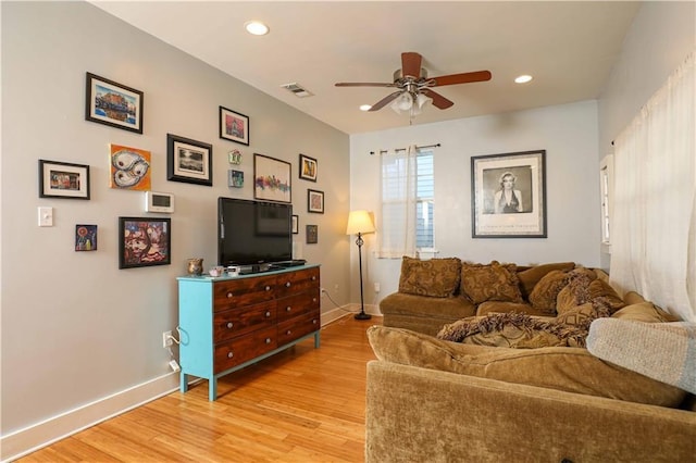 living room featuring baseboards, light wood-style floors, visible vents, and ceiling fan