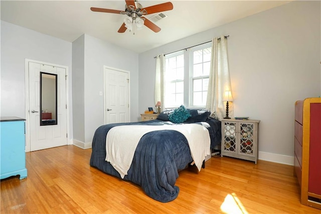 bedroom with visible vents, light wood-style flooring, a ceiling fan, and baseboards