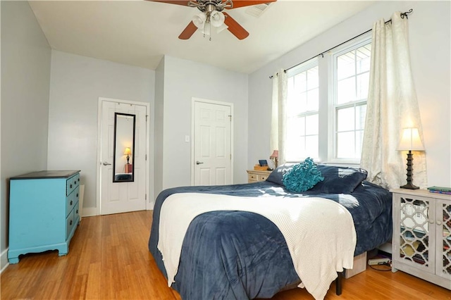 bedroom featuring light wood-type flooring, visible vents, and a ceiling fan