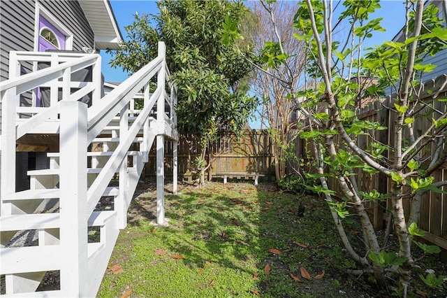 view of yard with a fenced backyard and stairs