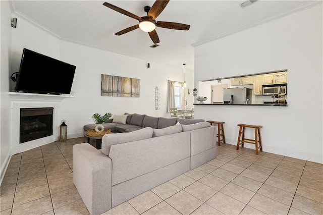 living area featuring visible vents, ornamental molding, a ceiling fan, a fireplace, and light tile patterned floors