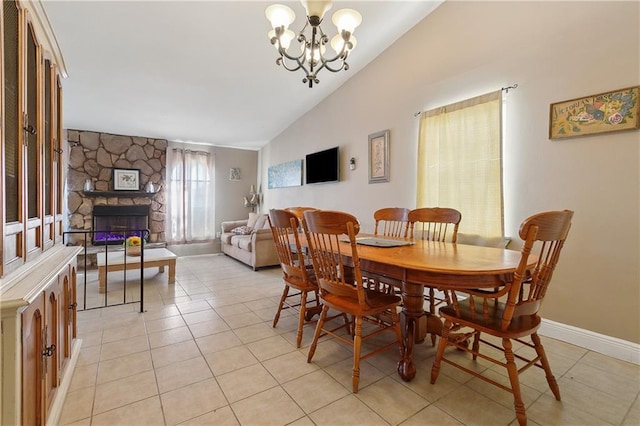 dining space featuring baseboards, vaulted ceiling, a fireplace, an inviting chandelier, and light tile patterned flooring