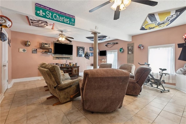 living room featuring a textured ceiling, light tile patterned floors, baseboards, and ceiling fan