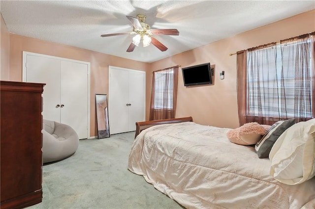 bedroom featuring multiple windows, a ceiling fan, two closets, and carpet floors